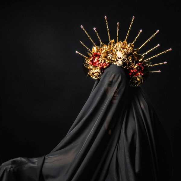 GHOST cover: a veiled figure in black under a gold crown of flowers and rays